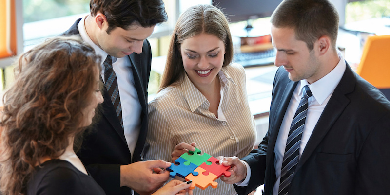 business people assembling jigsaw